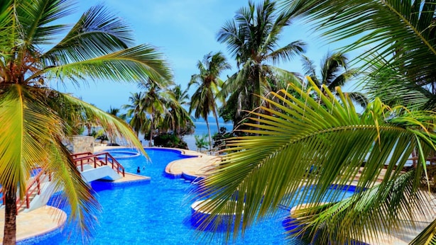 A pool area with multiple sections, palm trees, and a clear view of the ocean. - Stay.Plus Shanzu Beachfront Apartment (Mombasa)