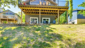 A two-story house with a covered deck, a stone retaining wall, and a grassy yard. - Reeds Spring Retreat w/ Lakeview Deck + Grill (Reeds Spring)