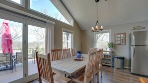 A spacious kitchen with a large wooden table, wooden chairs, a stainless steel refrigerator, and a hanging light fixture. - Reeds Spring Retreat w/ Lakeview Deck + Grill (Reeds Spring)