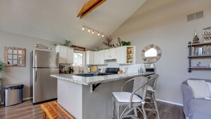 A modern kitchen with white cabinets, a stainless steel refrigerator, and a wooden bench. - Reeds Spring Retreat w/ Lakeview Deck + Grill (Reeds Spring)