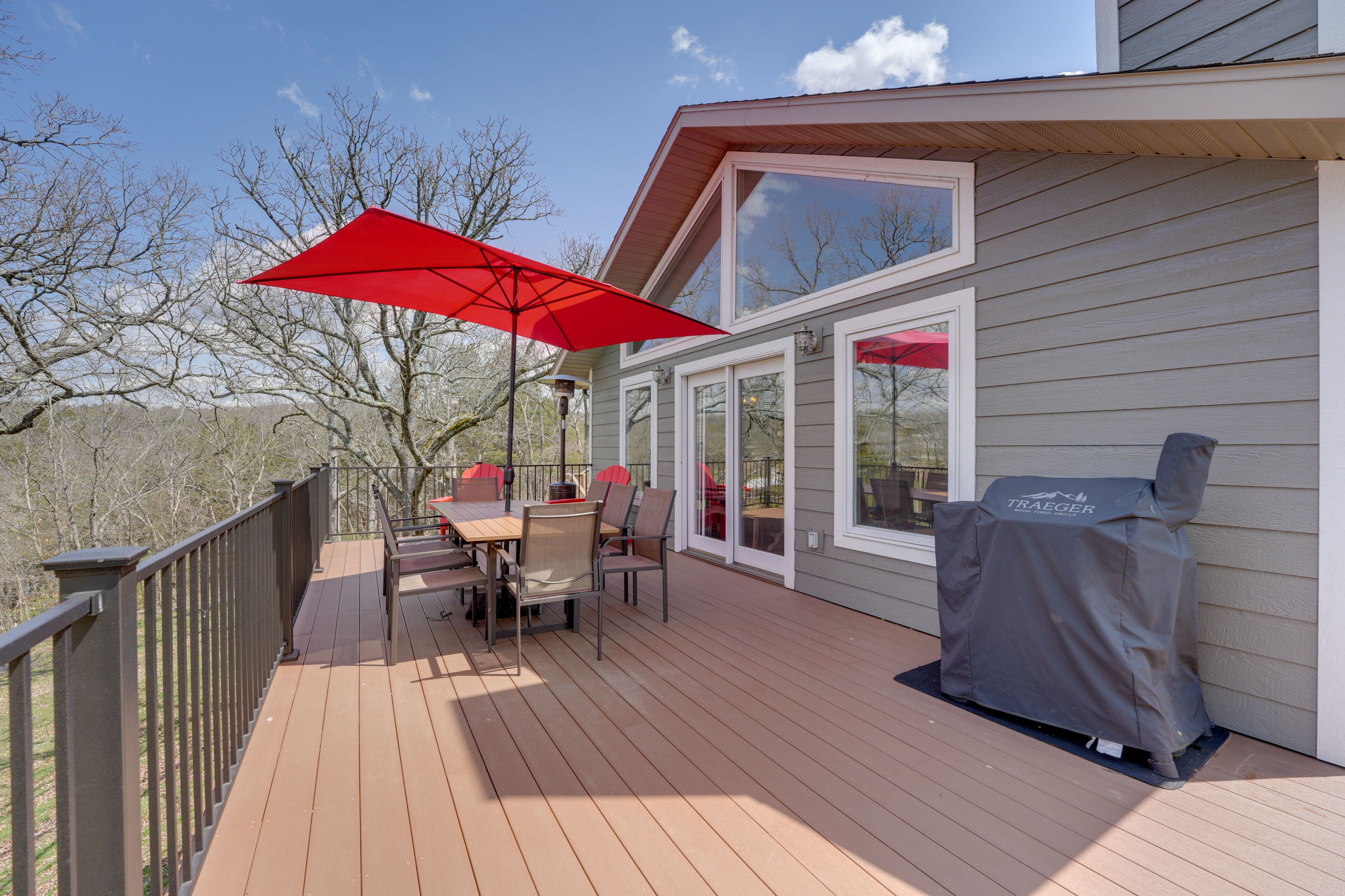 Eine Terrasse mit Tisch und Stühlen, einem Grill und einem roten Sonnenschirm.
