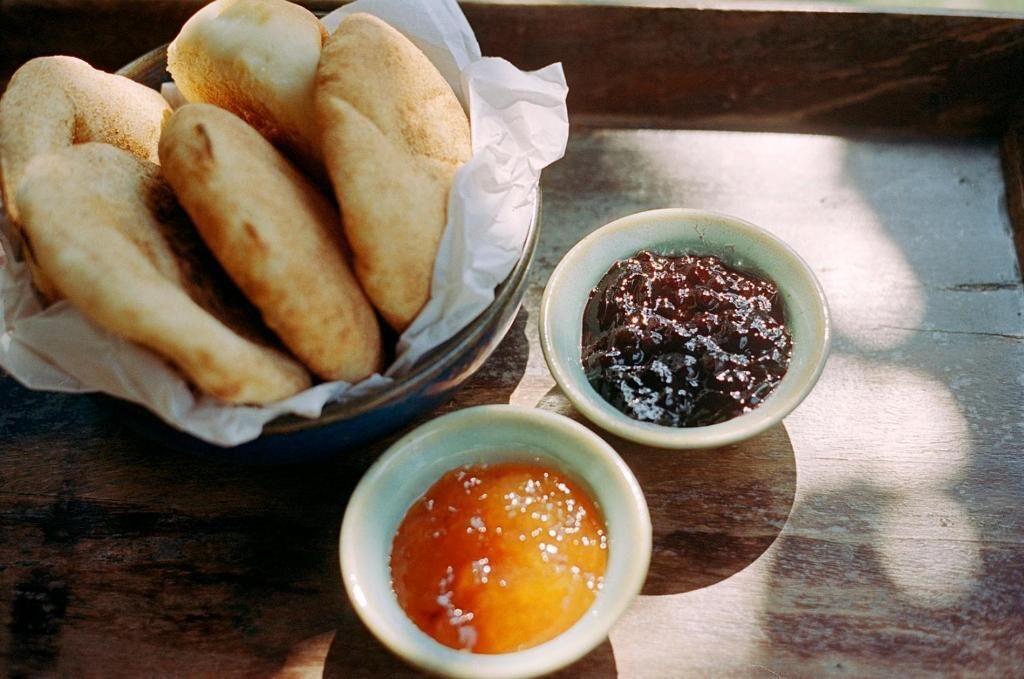 Una bandeja con panecillos y dos recipientes pequeños de mermelada.