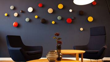 A modern room with two dark blue chairs, a wooden table, and a wall decorated with multicolored spherical objects.