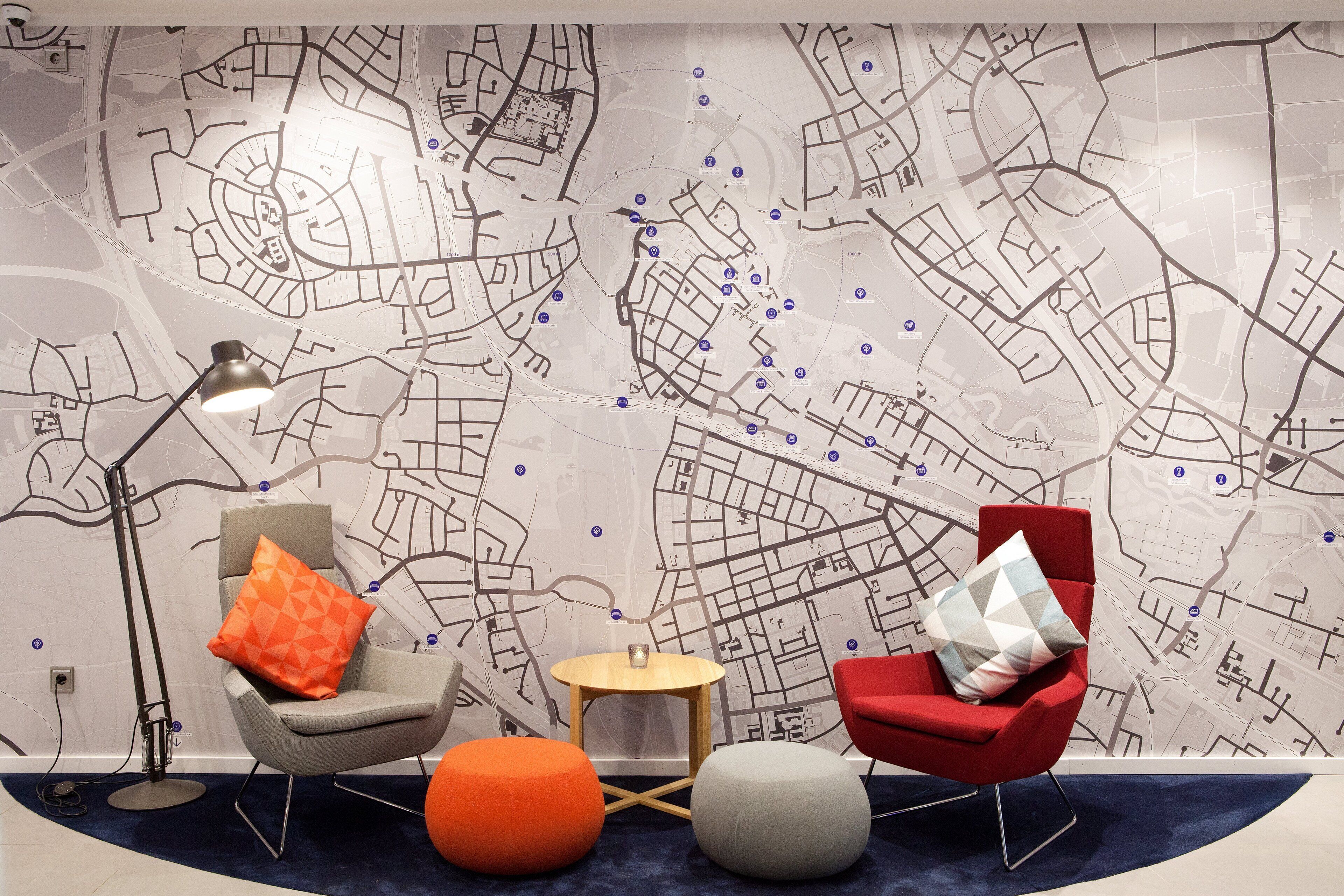 A modern room with a city map wall, two chairs, a small round table, and a floor lamp.