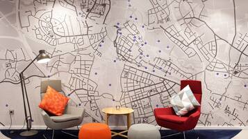 A modern room with a city map wall, two chairs, a small round table, and a floor lamp.