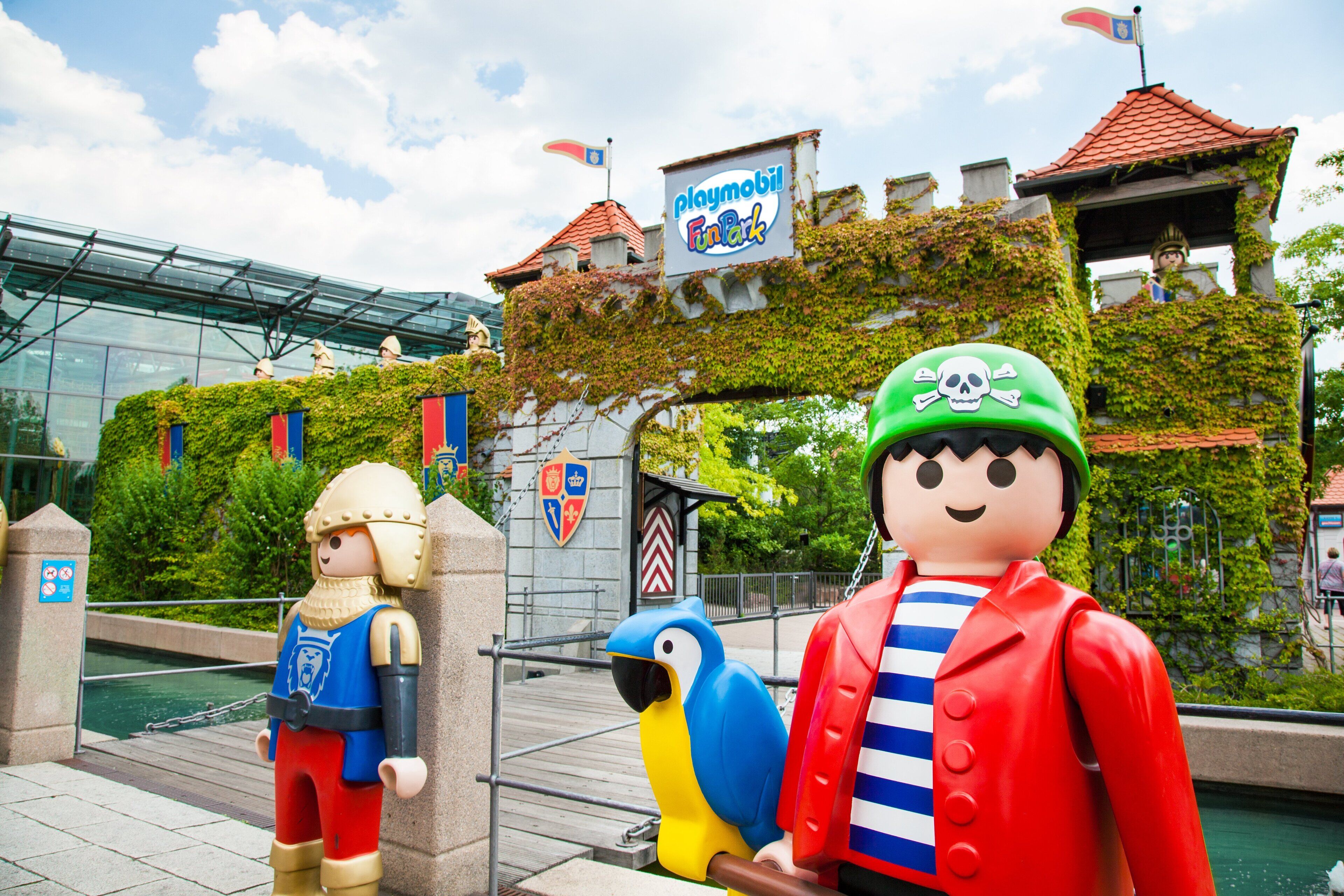 A playmobil-themed area with a glass building, a playmobil figure, and a parrot statue.