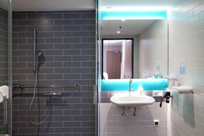 A modern bathroom with a glass shower enclosure, a white sink, and a mirror with a blue accent.