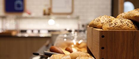 A wooden bread display with various types of bread, including rolls and baguettes, in a bakery setting.