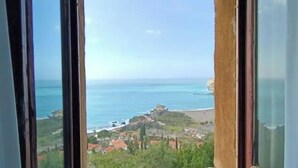 A coastal view through a window with a clear sky, a beach, and a small settlement with buildings.