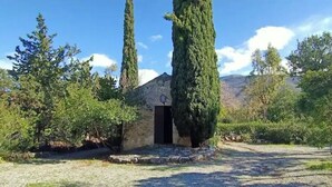 A rustic building with a stone entrance, surrounded by tall cypress trees and a gravel path leading to it. - Floresta Castle sea view (Praia a Mare)
