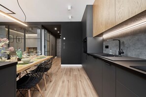 A modern kitchen with a wooden dining table, black chairs, and a black countertop.