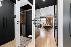 A modern kitchen with a dining area, a black refrigerator, and a glass partition.