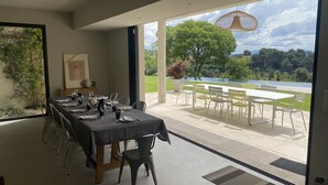A dining area with a table set for six, a view of a lake, and a garden outside. - House, pool, 4 or 6 bedrooms, with views of the Aix countryside  (Éguilles)