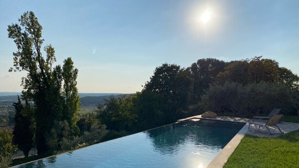 A clear view of an infinity pool with a grassy edge, surrounded by trees and a distant landscape. - House, pool, 4 or 6 bedrooms, with views of the Aix countryside  (Éguilles)
