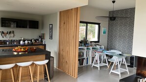 A modern kitchen with a central island, bar stools, and a dining area with white chairs. - House, pool, 4 or 6 bedrooms, with views of the Aix countryside  (Éguilles)