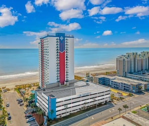 Un hotel de gran altura con estacionamiento, vista a la playa y cielo despejado.