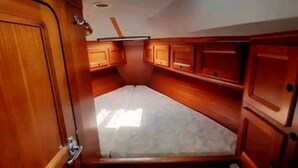 Un camarote náutico compacto con tragaluz, armarios de madera y un banco.