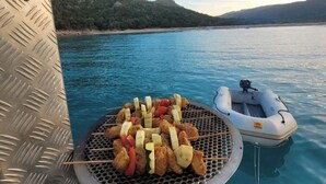 Una parrilla con brochetas de carne y verduras en un bote.