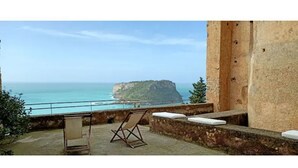 A balcony with a view of the sea and a cliff. There is a folding chair and a cushion on the balcony. - Castle for 16 Guests (Praia a Mare)