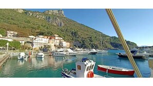 A marina with boats docked, a mountainous backdrop, and buildings along the waterfront. - Castle for 16 Guests (Praia a Mare)