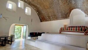A spacious room with a high, rustic ceiling, a white sofa, a small table, and a bench. - Castle for 16 Guests (Praia a Mare)