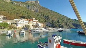 A marina with boats docked, a mountainous backdrop, and buildings along the waterfront. - Castle for 16 Guests (Praia a Mare)