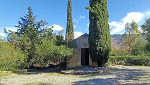 A rustic stone building with a dark entrance, surrounded by greenery and tall trees. - Castle for 16 Guests (Praia a Mare)