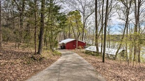 A red cabin with a metal roof, surrounded by trees and a path leading to it. - Lakefront Lavonia Cottage w/ 2-Story Dock! (Lavonia)