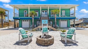A beachfront property with a two-story building, a fire pit, and two beach chairs. - Just a short walk to beach access, Sleeps 12 (Navarre)