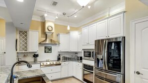 A modern kitchen with white cabinets, stainless steel appliances, and a marble countertop. - Just a short walk to beach access, Sleeps 12 (Navarre)