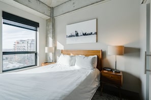 Relax in a spacious room with a large bed, two nightstands, and a city view.