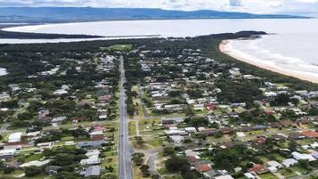 An aerial view of a coastal residential area with houses, roads, and a beach.