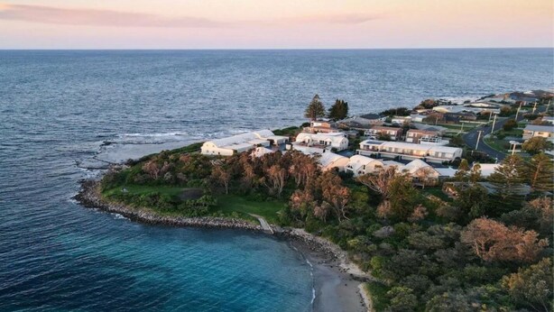 An aerial view of a coastal residential area with houses and a beach. - Blondie's – beach at the end of the street (Culburra Beach)
