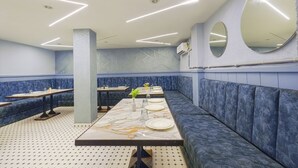 Um restaurante com assentos estofados em azul, mesas de mármore e iluminação moderna.
