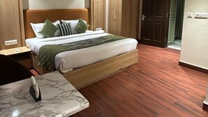 Quarto de hotel com cama, escrivaninha, cadeira, ventoinha no teto e armário.