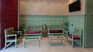 Quarto com lambris verde, porta vermelha e televisão de tela plana fixada na parede.