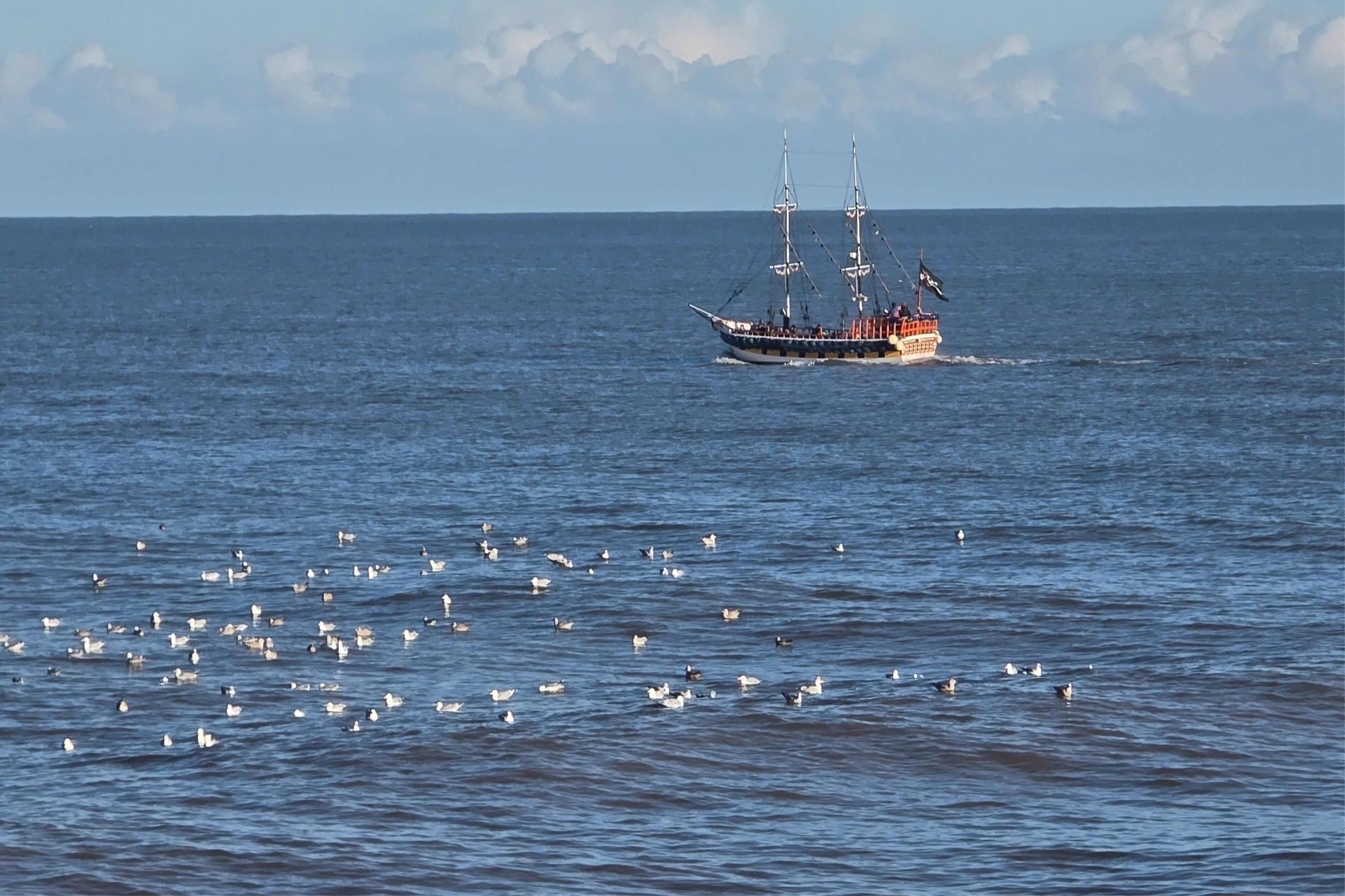 A boat with passengers on a calm sea.
