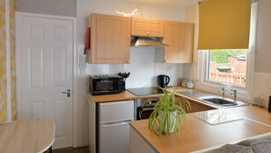 Cocina compacta con microondas, tostadora, lavabo y un refrigerador pequeño.