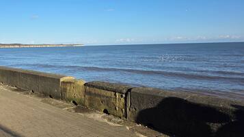 A coastal walkway with a concrete barrier and a paved path.