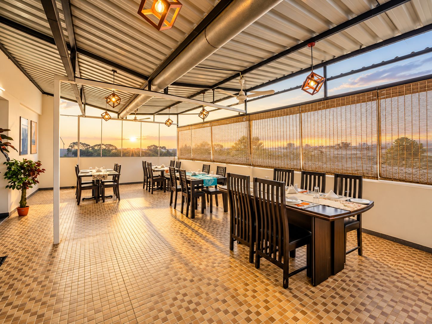 A restaurant with a terrace, tables, chairs, and a view of the sunset.