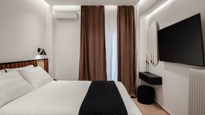 Una camera d'albergo moderna con un letto grande, una TV a schermo piatto, un comodino e una finestra con tende.