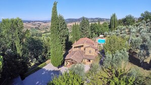 Une villa avec un toit en tuiles, entourée d’oliviers et dotée d’une piscine.