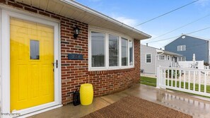 A residential house with a yellow front door, a brick exterior, and a white fence. - Newly Redecorated Beach Home in Wildwood Crest (Wildwood Crest)