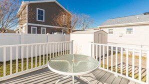 A fenced outdoor area with a round table and chairs, a wooden deck, and a house in the background. - Newly Redecorated Beach Home in Wildwood Crest (Wildwood Crest)
