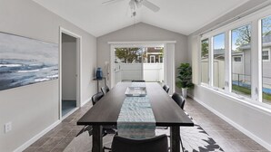 A dining area with a long table, chairs, a ceiling fan, and a view through large windows. - Newly Redecorated Beach Home in Wildwood Crest (Wildwood Crest)
