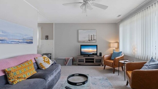 A modern living room with a grey sofa, a brown leather armchair, a flat-screen TV, and a ceiling fan. - Newly Redecorated Beach Home in Wildwood Crest (Wildwood Crest)
