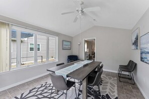 Un espace repas comprenant une longue table, des chaises et un ventilateur de plafond.