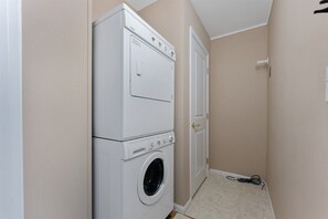 A laundry room with stacked washers and dryers, a door, and a visible power cord.