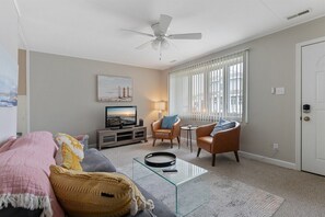 Un salon comprenant un canapé, un fauteuil, une table basse en verre et un téléviseur.