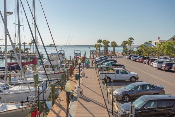 A marina with boats docked, a parking area with cars, and a clear view of the water.